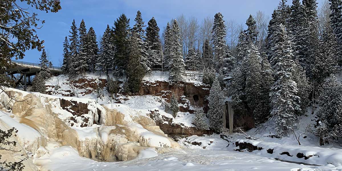 snow dusted pines, frozen waterfalls and river at gooseberry fall state park