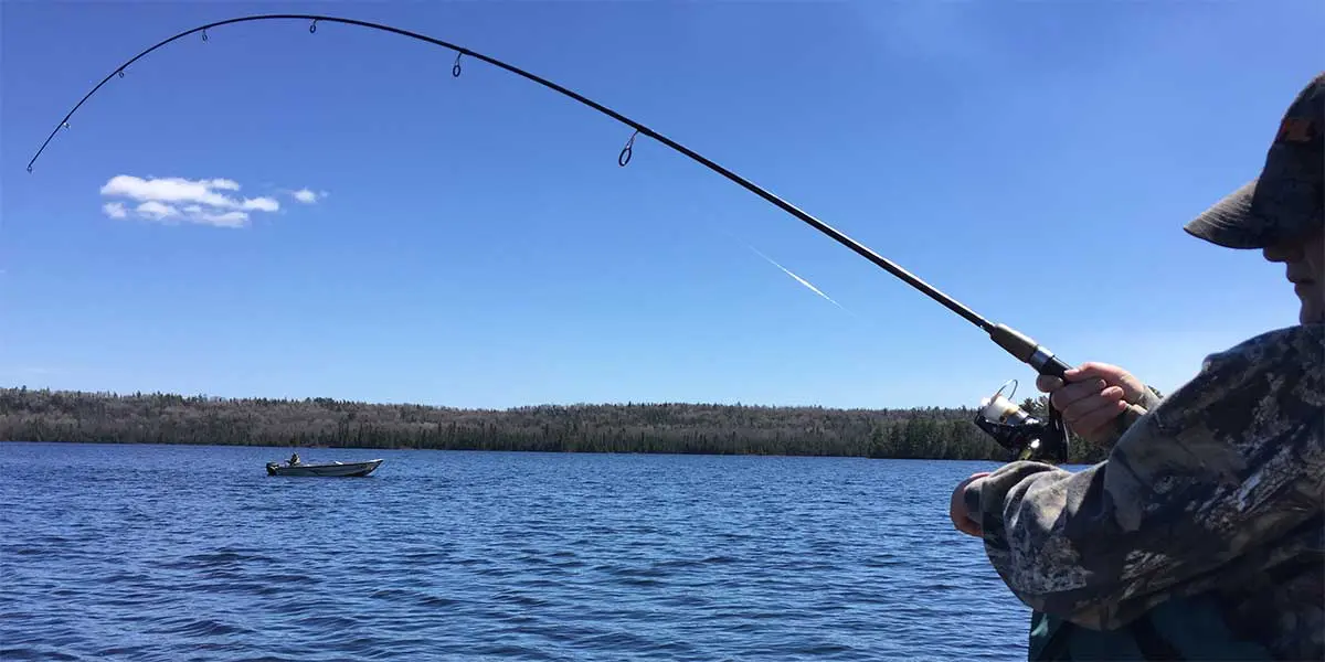 walleye fisherman with bent rod and another fishing boat