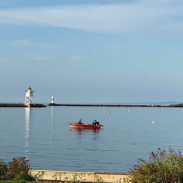 two men in a red and silver fishing boat in the grand marais mnm harbor