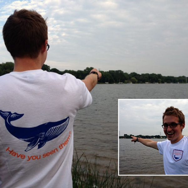 man in whale watching t-shirt points them out