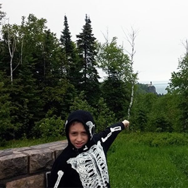 boy in skeleton jacket pointing to whale