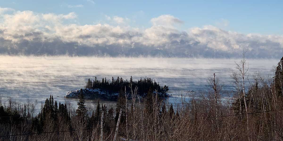 See smoke rises behind an island in Lake superior