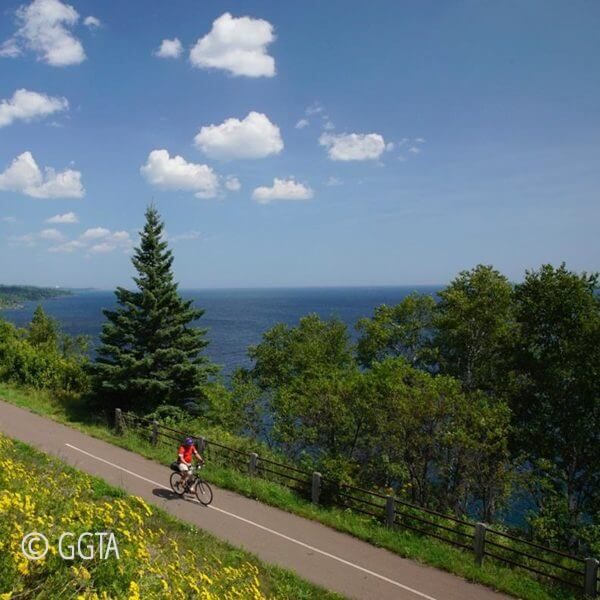 bike rider on gitch gami bike trail along shore of Lake Superior between gooseberry falls and split rock lighthouose