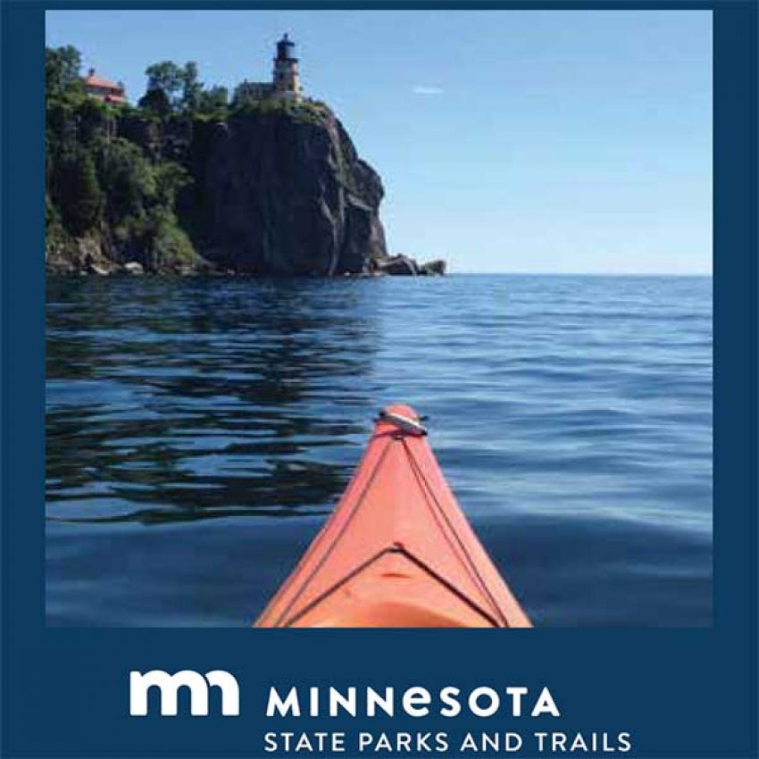 lake-superior-kayak-trail-map2 looking over nose of red kayak at split rock lighthouse up on a stone cliff