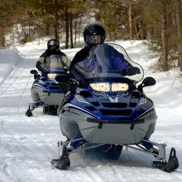 close up of two snowmobilers coming down a trail in grand portage