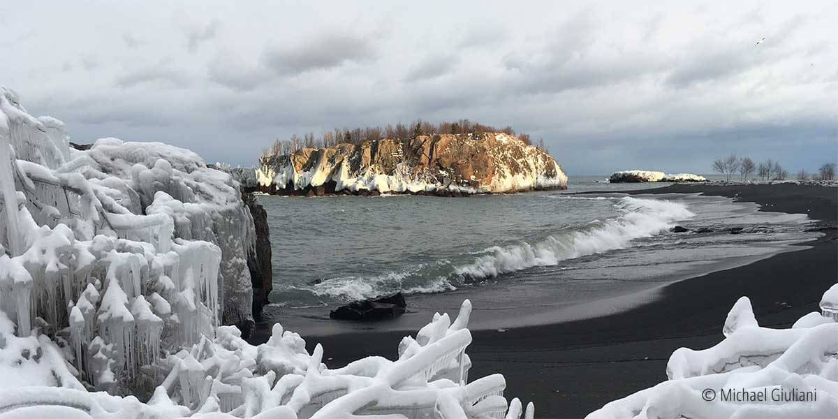 black beach, island and icy lake superior shoreline