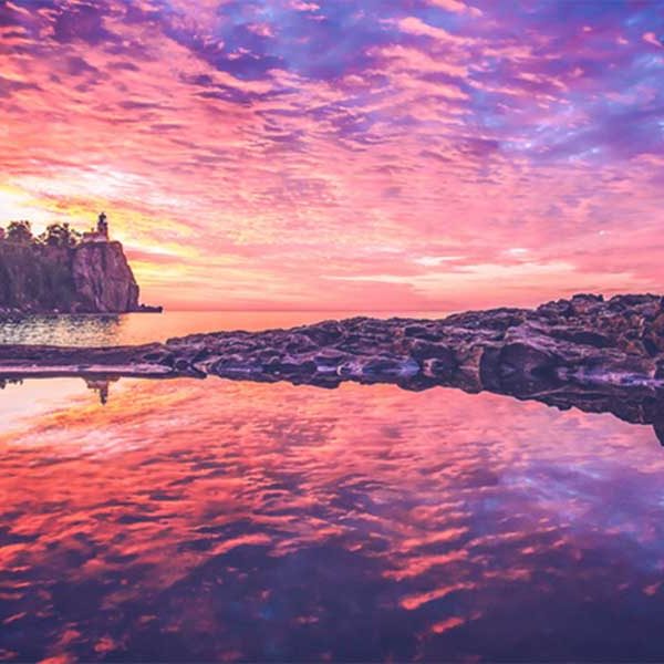 pinks oranges purples of sunrise with clouds over split rock lighthouse