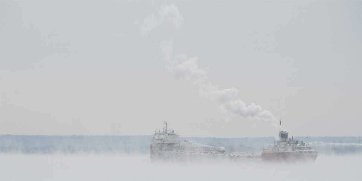 sea smoke rises around a ship in lake superior